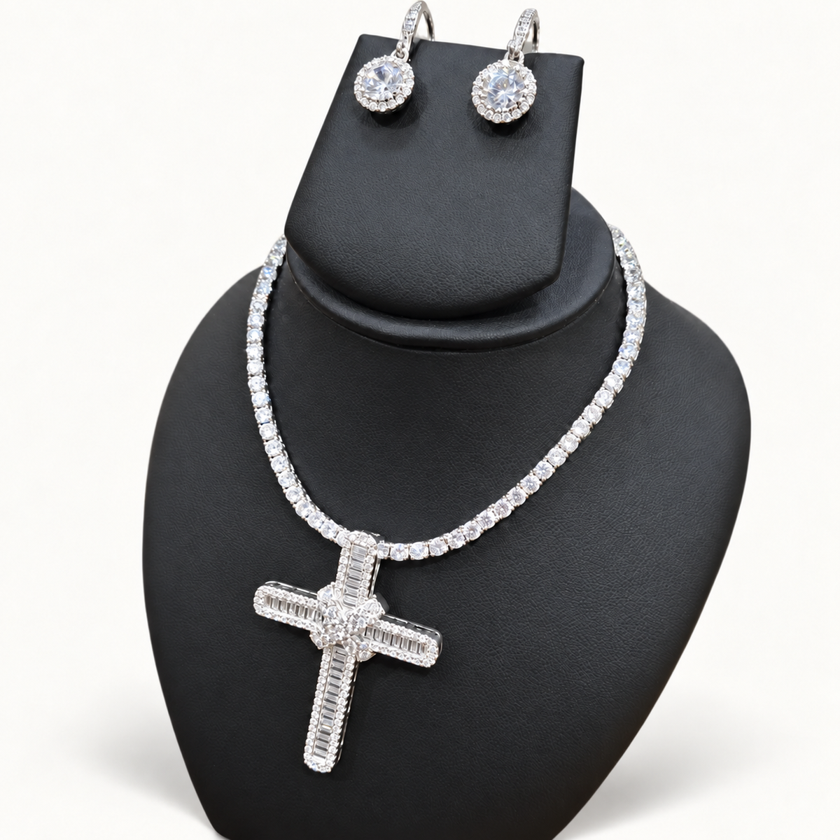 Silver CZ cross set on black bust against neutral ivory studio background